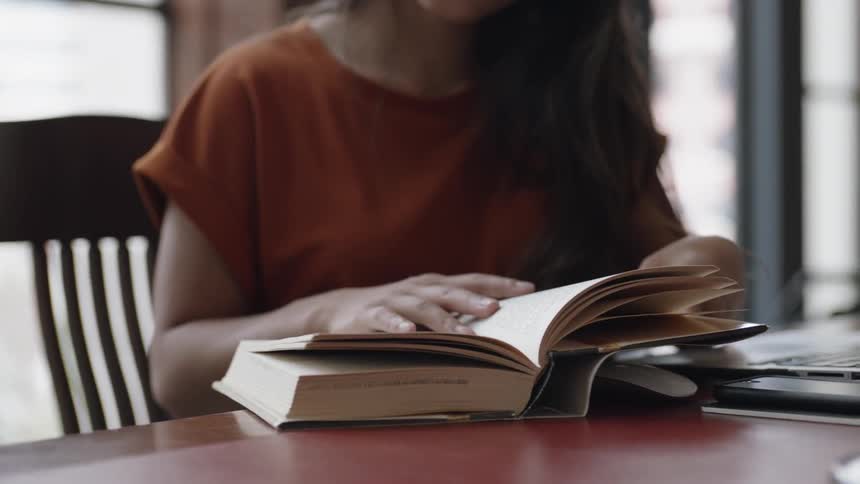 Young woman grabbing book to look at page
