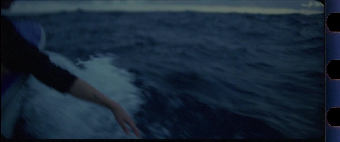 Female hand touching the ocean from a boat while moving