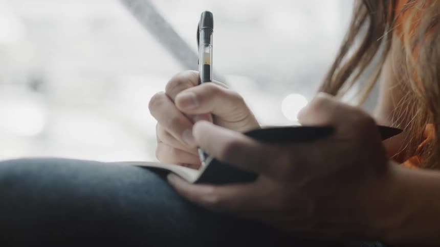 Hand holding pen to write in journal