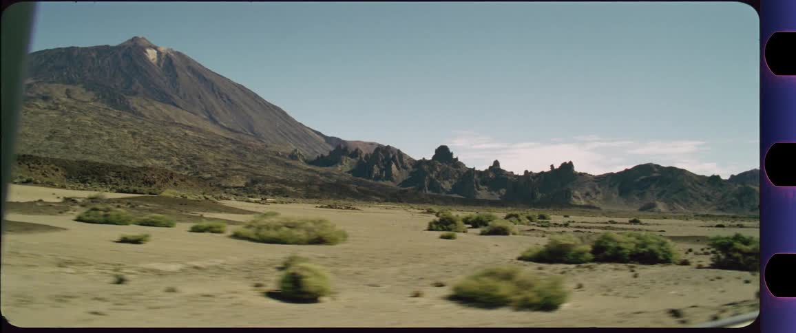 Mountain behind desert scenery shot out of a driving car