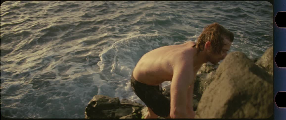 Man climbing up rocks next to the ocean