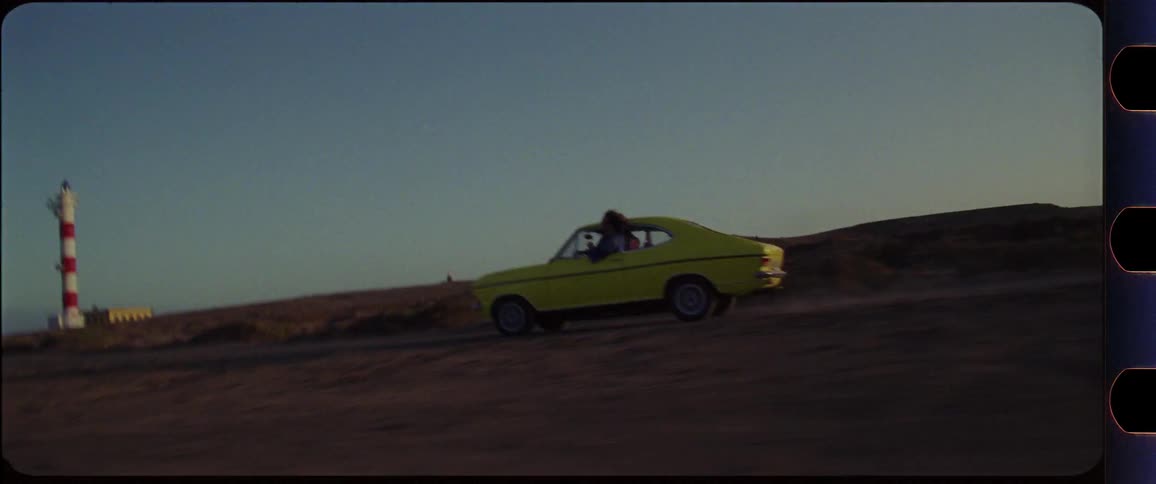 yellow car driving through desert mountain region at sunset with drivers climbing out the window