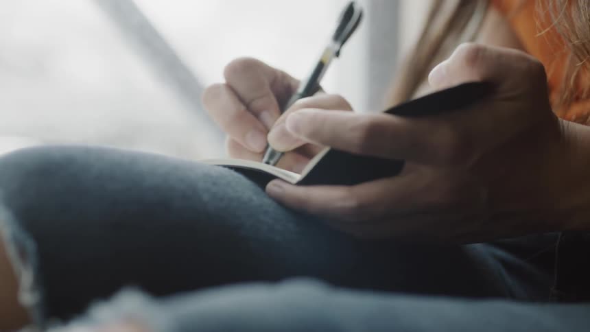 Hand holding pen to write in notebook