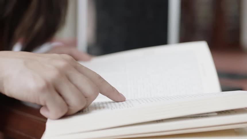 Hand and fingers following words in a book