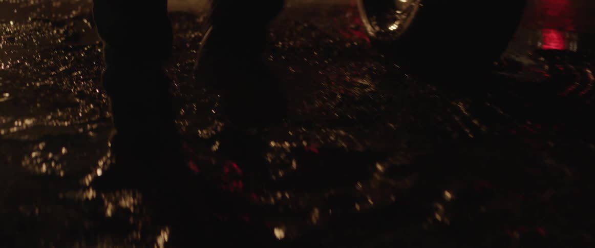 Up close view of person's feet getting out of a car walking through the mud