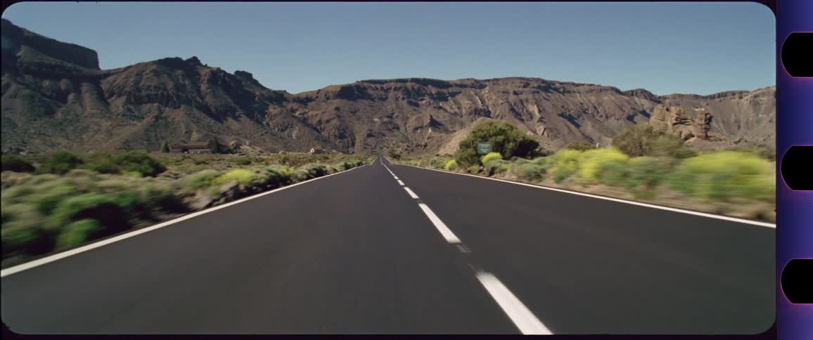 Camera flying above a highway with mountains in the background