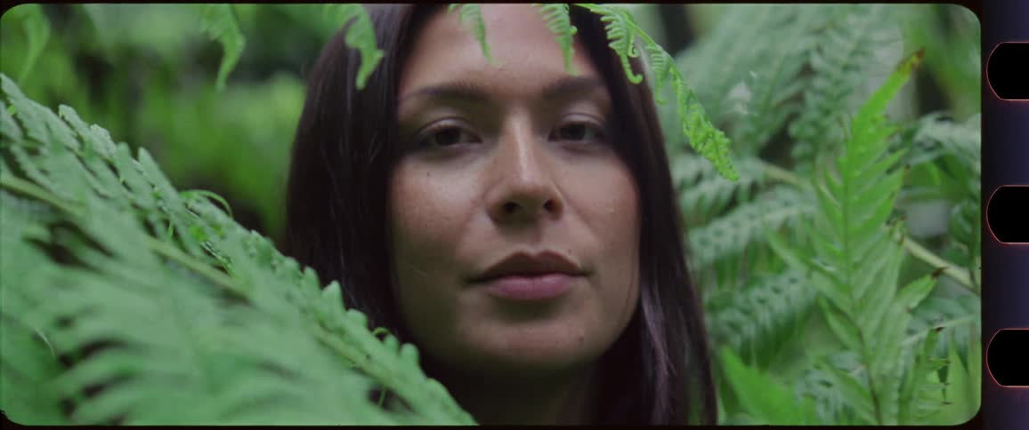 Woman looking up and disappearing behind fern
