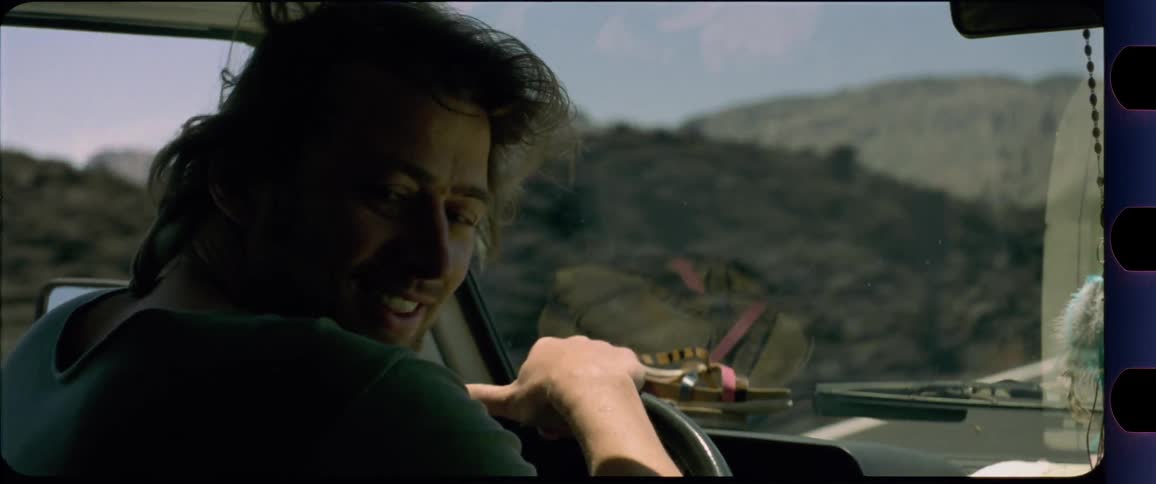 Man sticking his head out the window and is excited while driving through desert scenery