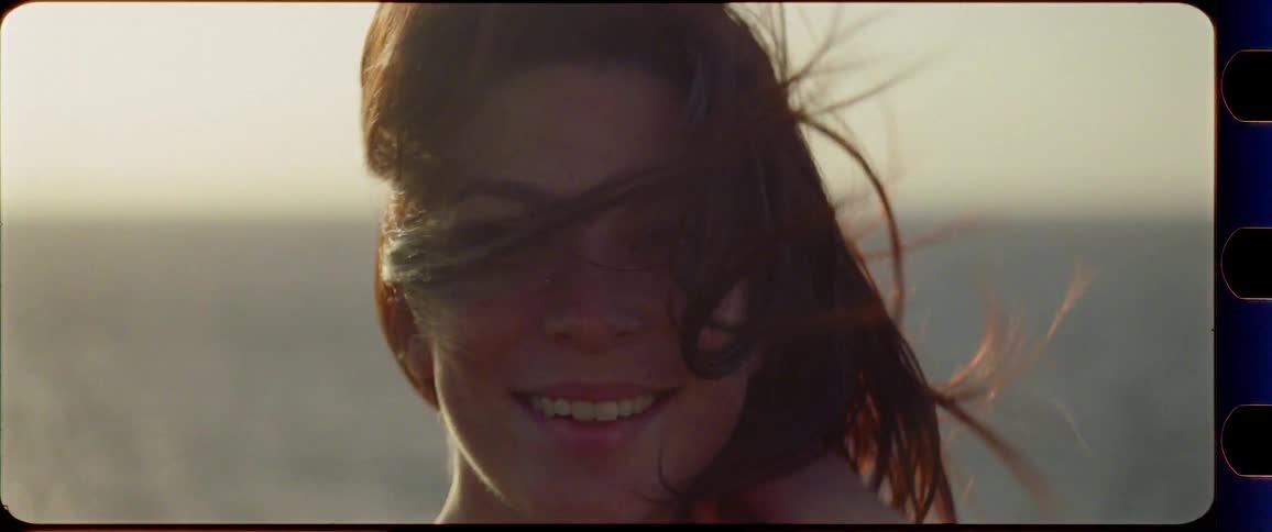 Woman enjoys the sunset by the ocean with wind in her hair