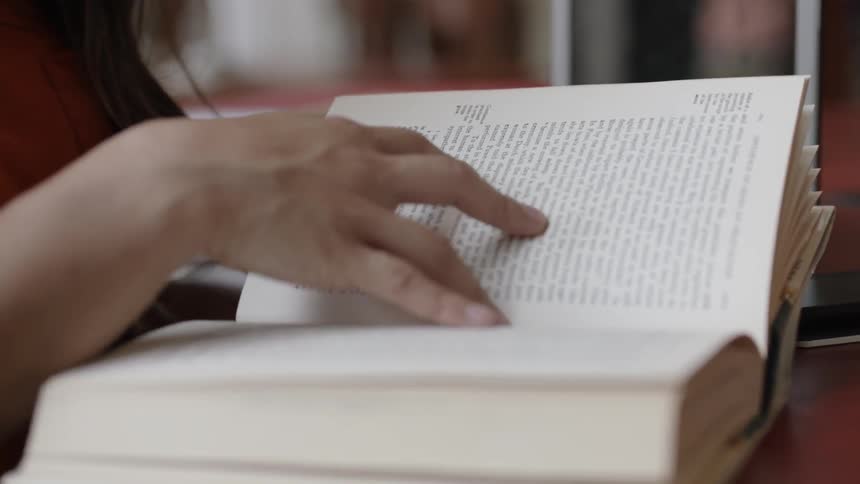 Fingers scanning through a book at desk