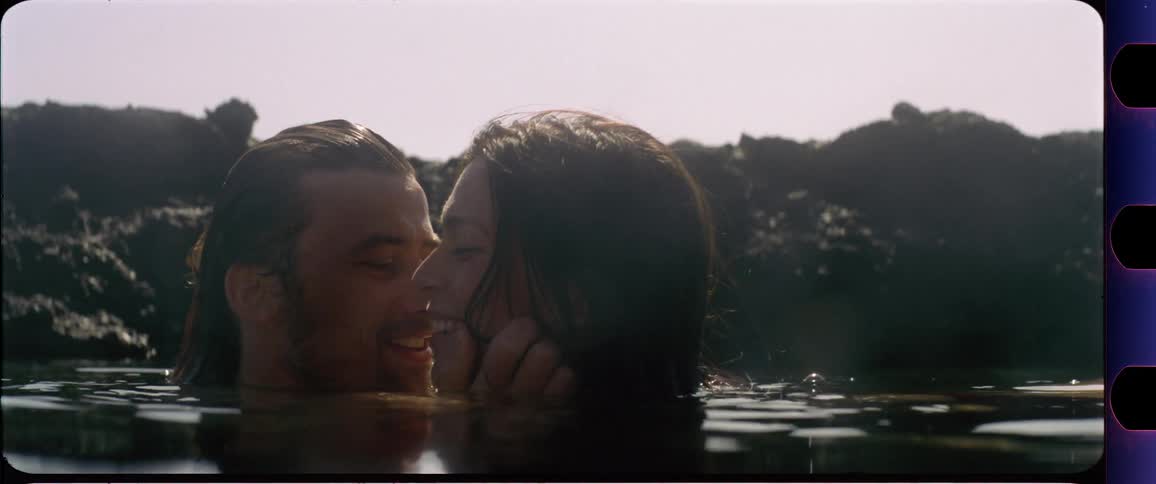 Couple in the water moving closer and laughing