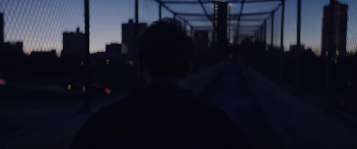 Man crossing a city bridge at night