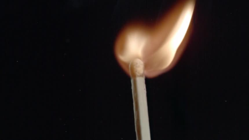 A lit match burns in a dark room