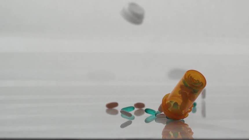 Bottle of pills falling with pills flying all over