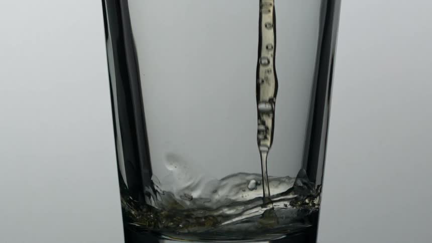 Brown liquid slowly dropping then pouring into a glass