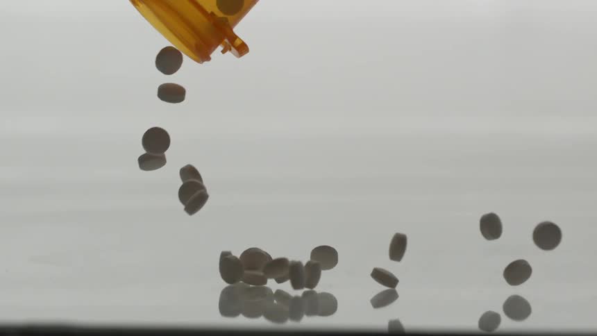 Bottle of pills falling with pills flying all over