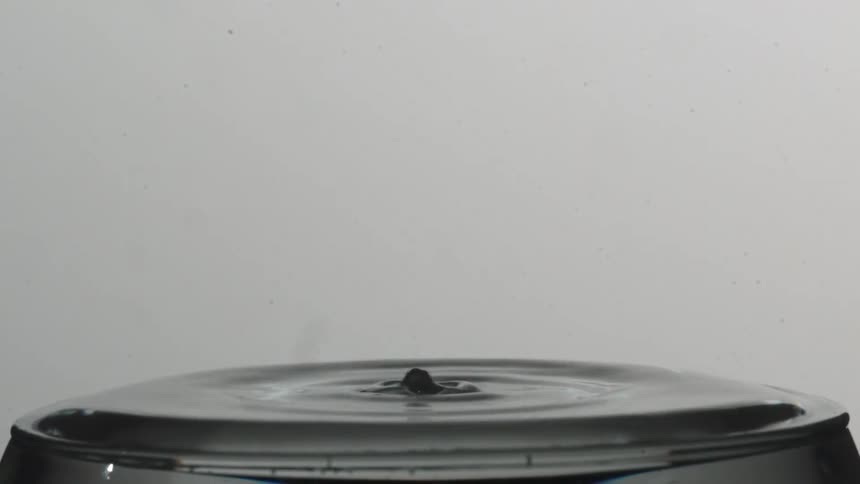 A drop of liquid hits the surface causing a splash and ripples
