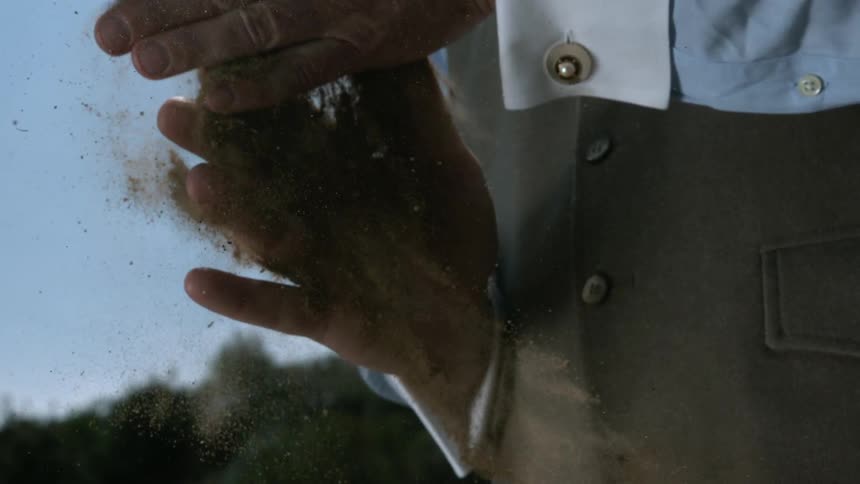 A man holding dirt and slapping his hands together
