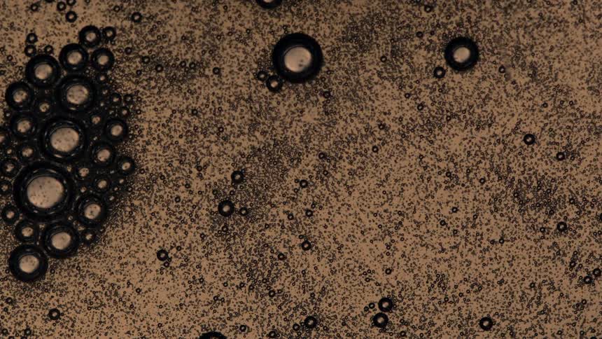Abstract of black colored bubbles floating in a liquid suspension