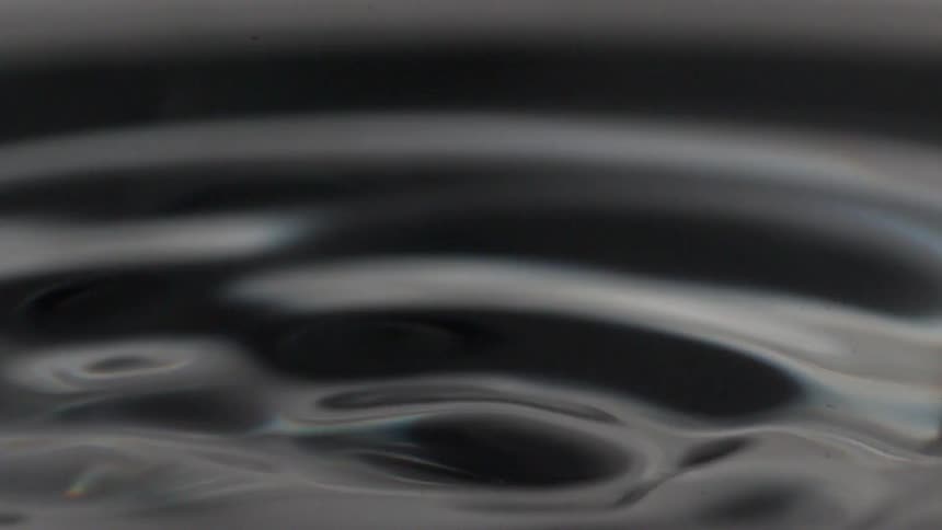 A close view of a drop of water falling into water in slow-motion