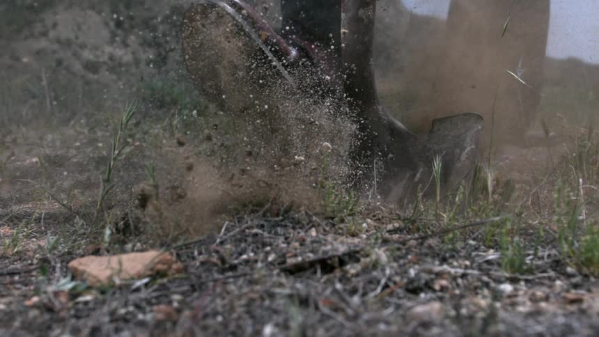 A foot pushes the head of a garden shovel into the dirt