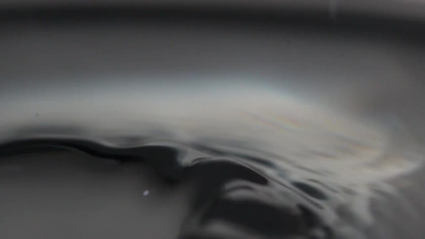 Abstract close up of water rippling with a water drop falling into it