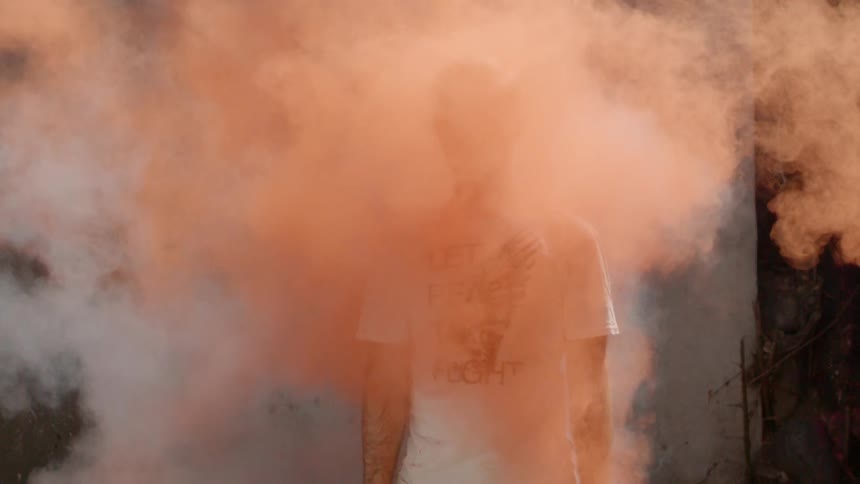 A man walks through a cloud of colored dust