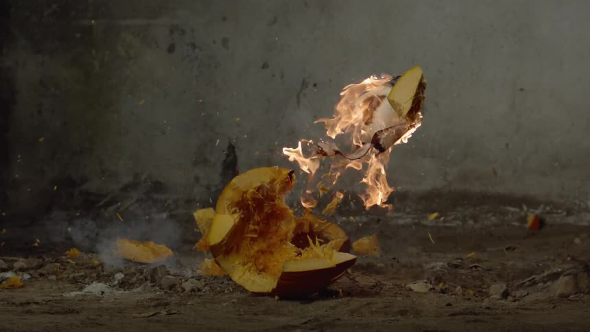 A burning jack-o-lantern crashes to the ground and bursts open