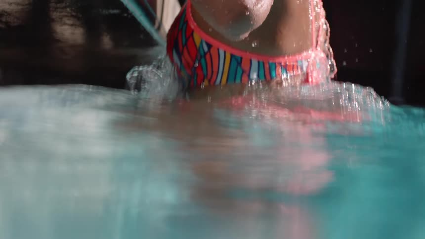 Slow motion of a woman's body as she climbs out of a pool