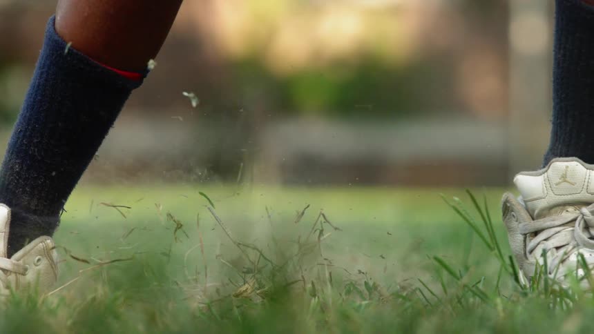 Boy in sneakers sliding on grass