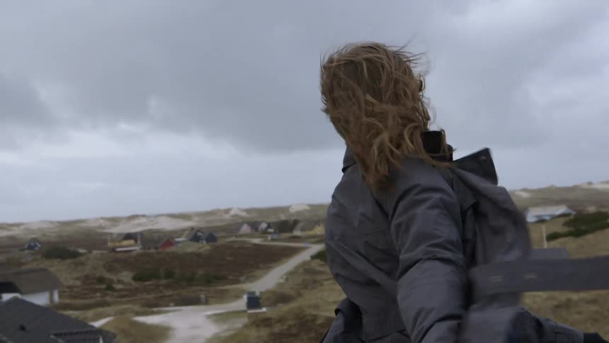 A woman spins in circles outside in the wind