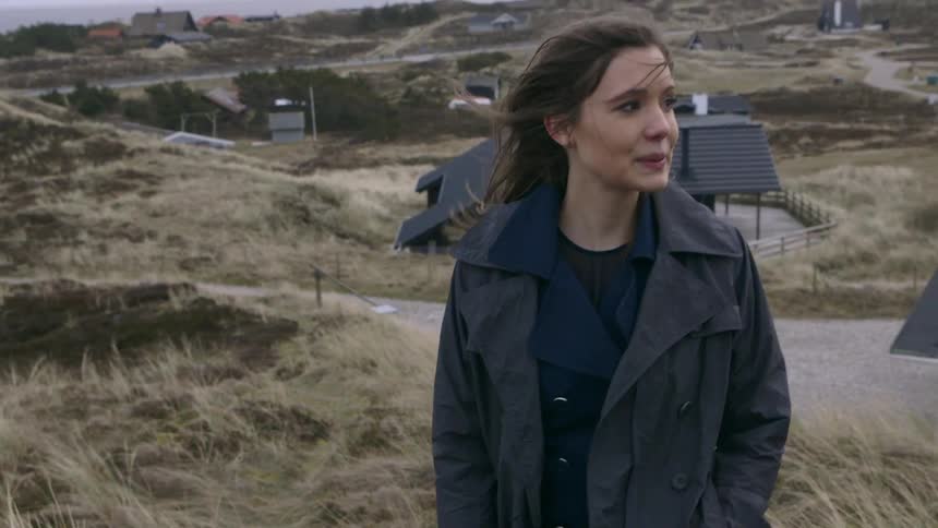 Woman walking slowly up a hill on a windy day