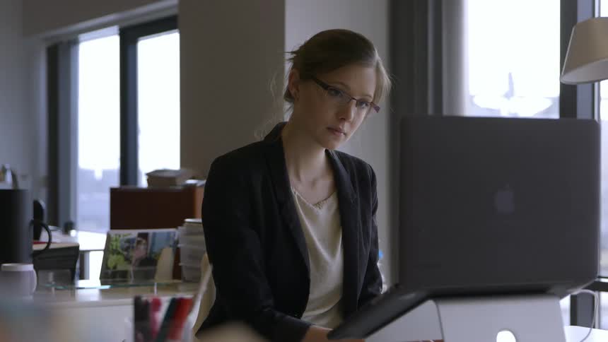 A woman wearing glasses sitting in front of a computer