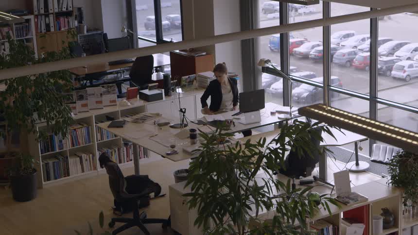 A woman in a dark jacket leans back in her office chair