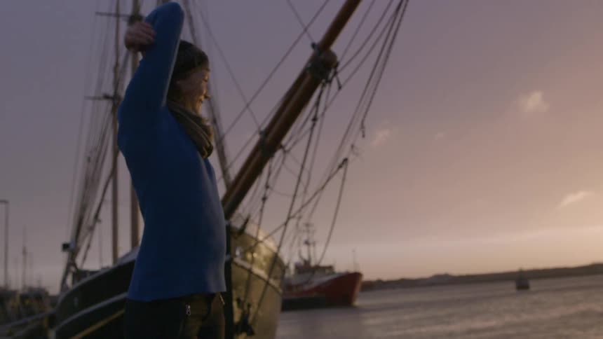 A woman enjoying the sunset next to a ship