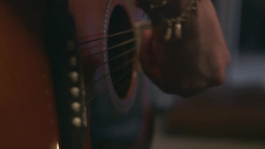A person is playing a guitar with a guitar pic