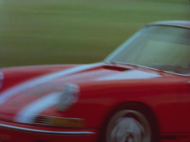 Vintage cars are racing back and forth on a track on a cloudy day