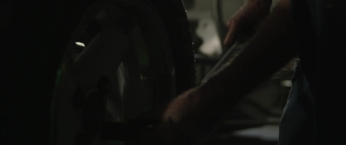 Man changes a tire in a dim garage