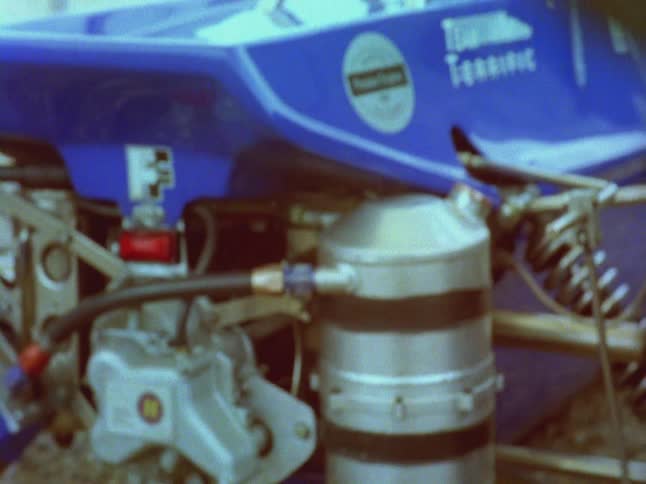 Old footage of a race car driver and then the race car moving