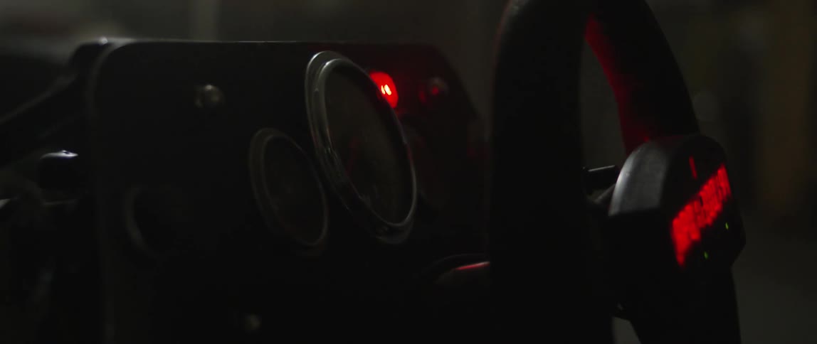 A person pushes a starter and lights blink on a dashboard and steering wheel