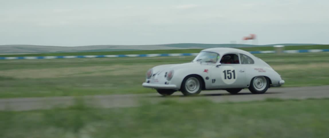 Cars are racing down a track on a cloudy day
