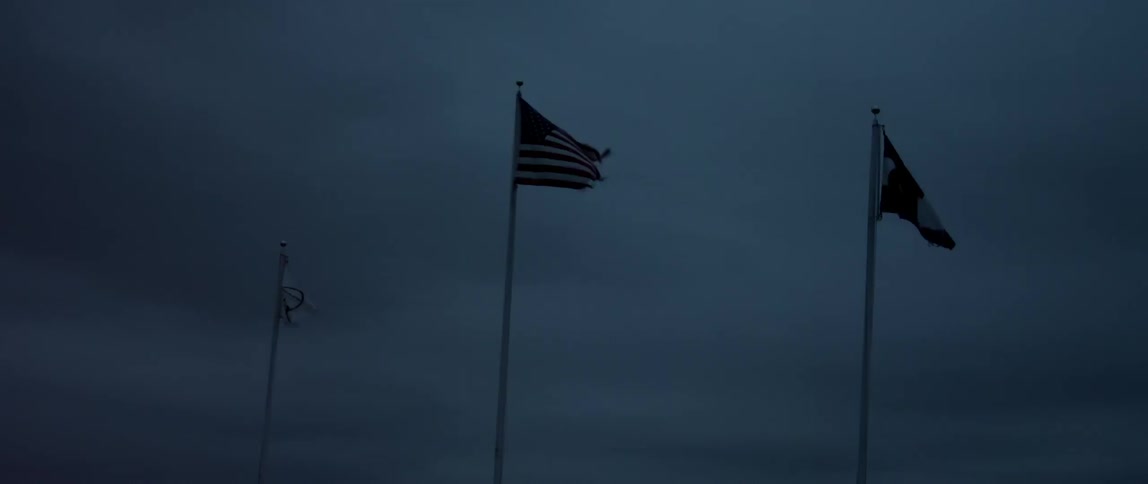 Three flags blow in the wind on a windy night