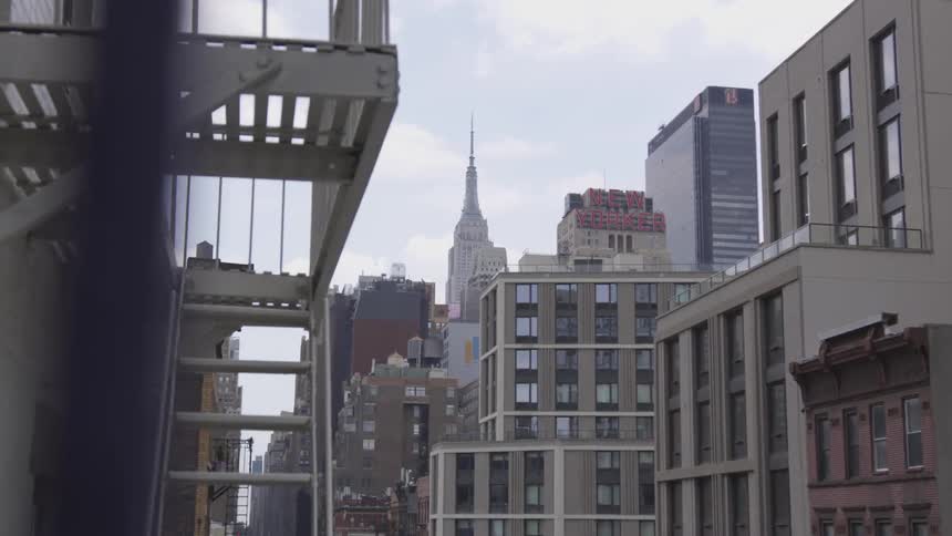 A fire escape hangs before several towering buildings in a gray downtown area