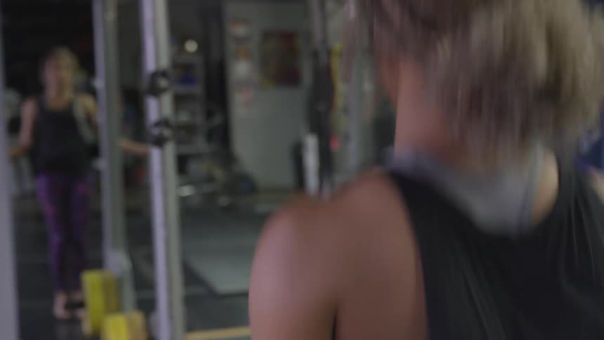A woman watches her reflection in the mirror as she jumps rope at the gym