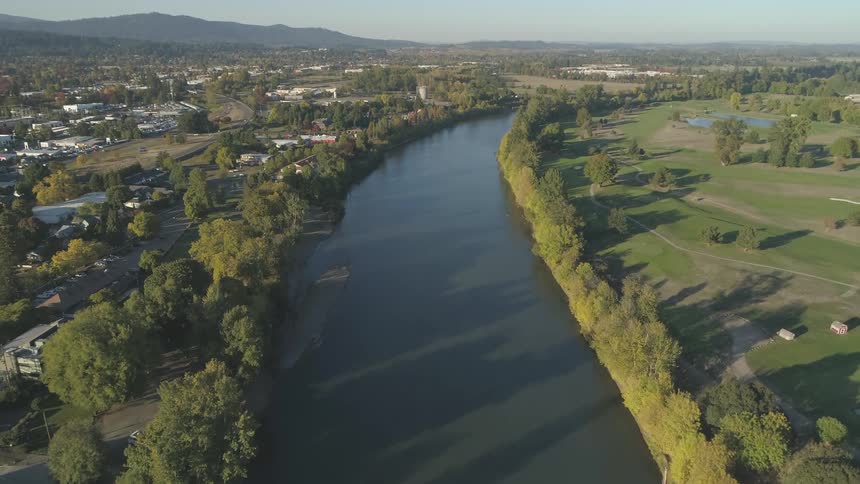 Overview of river separating parkland and town with mountains in distance