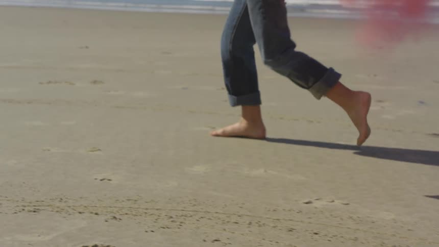 Red and blue smoke billow out behind a child running on the beach