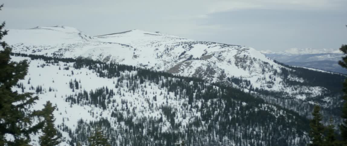A large mountain range is covered in snow on a cloudy day