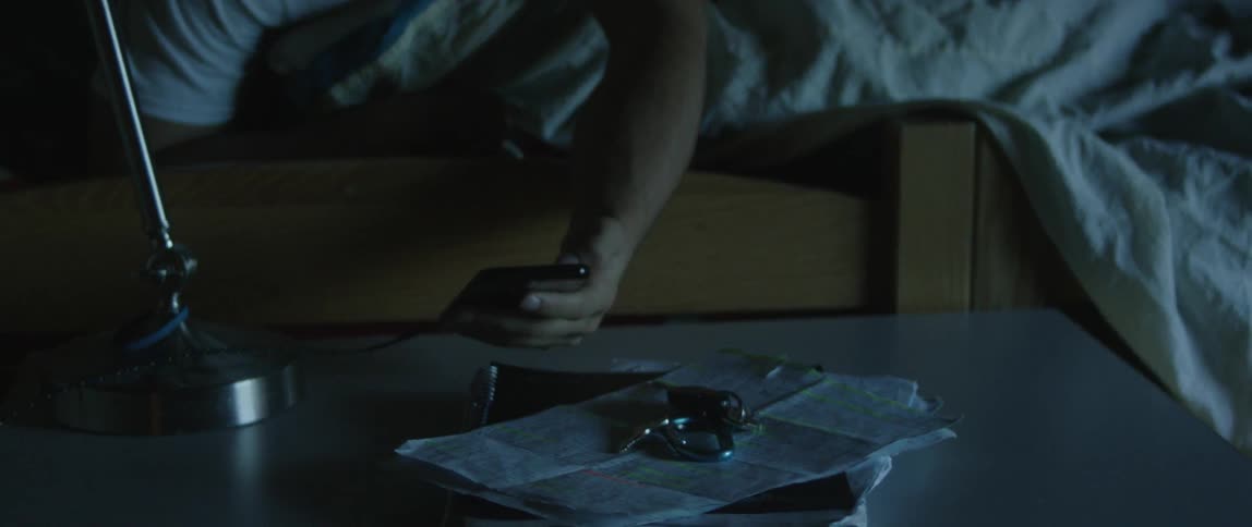 A man lying in bed checks his phone and then rushes out of bed