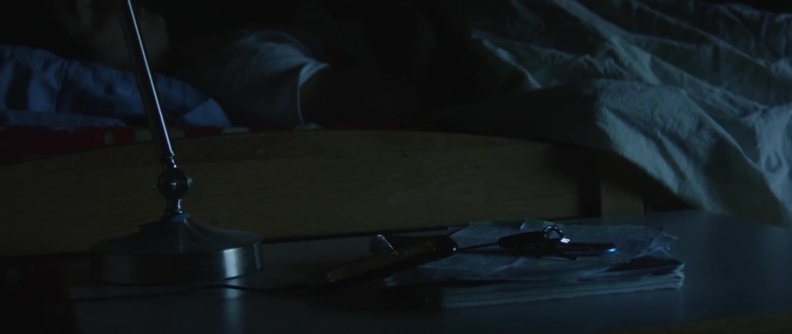 A man wakes from sleep and quickly checks his phone that is laying on a nightstand