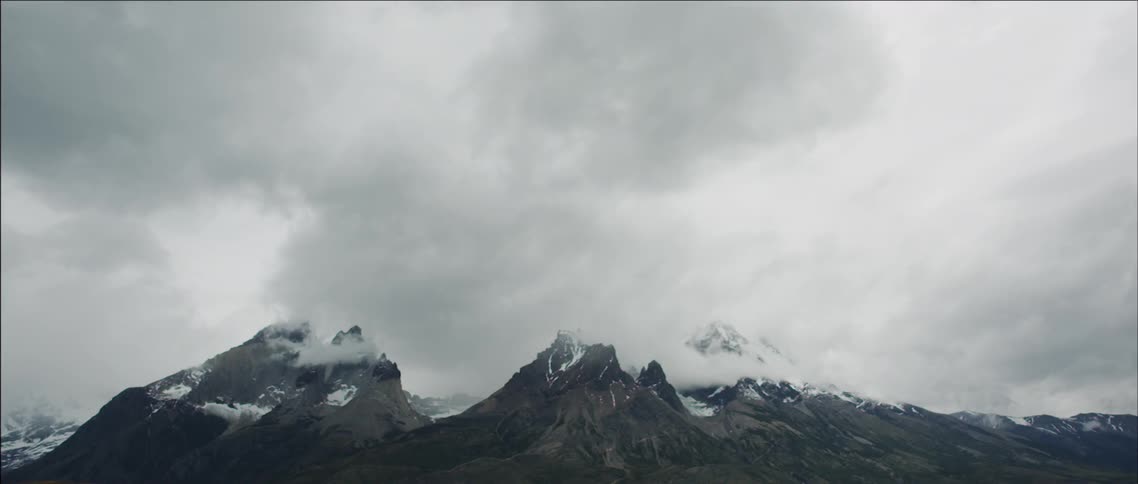Large clouds are covering a rocky mountainside